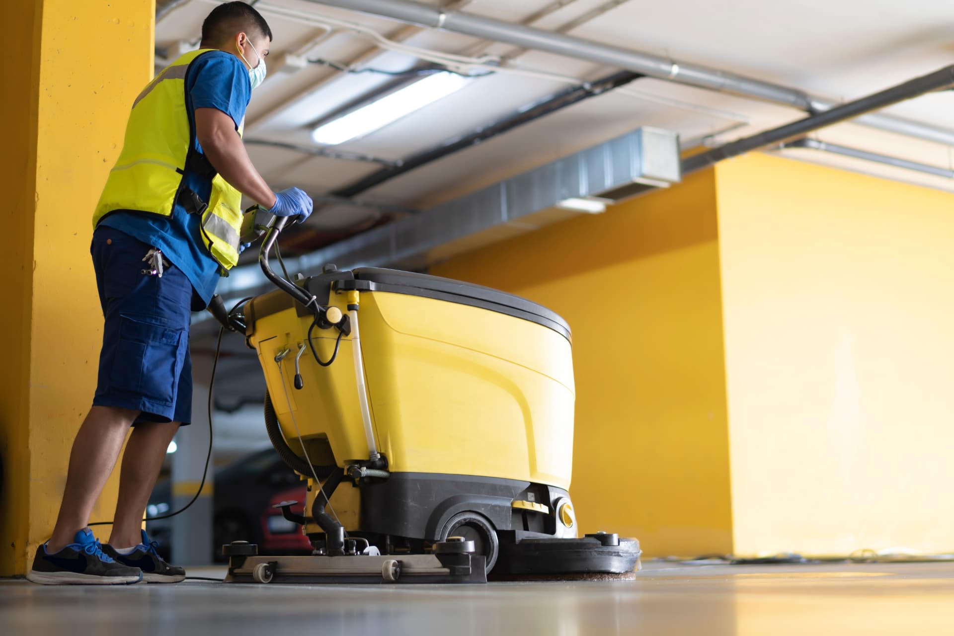 Opérateur conduisant une autolaveuse sur le plancher d'un stationnement intérieur