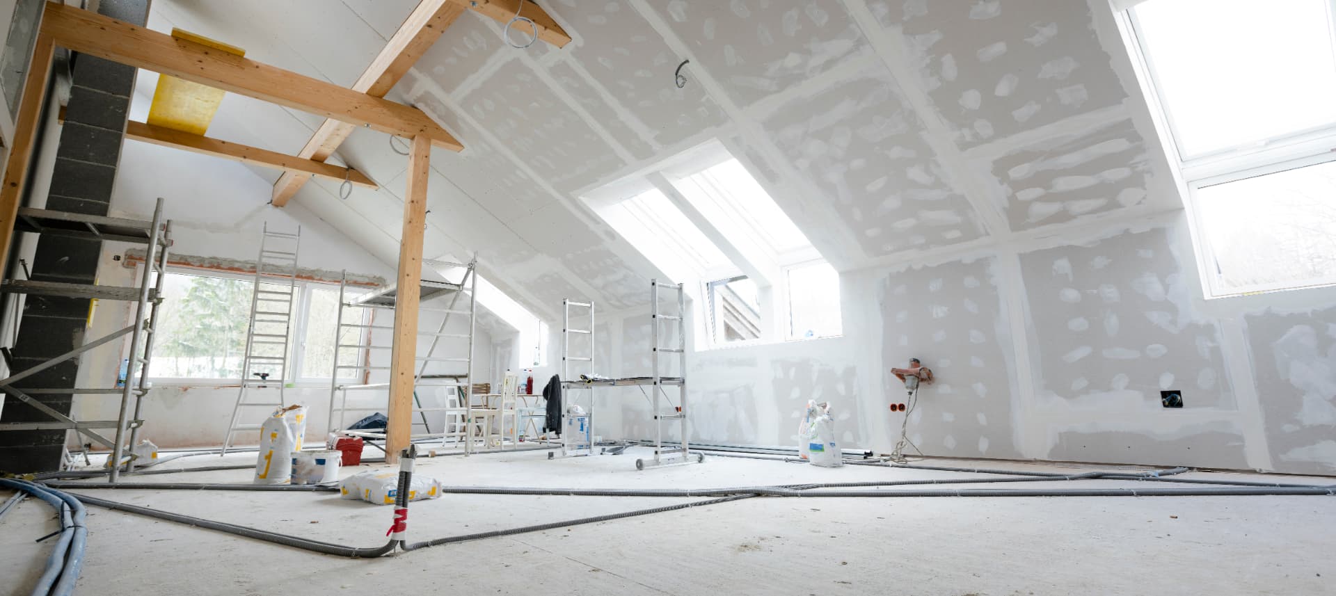 Local en fin de chantier : cloisons de gypse jointées, échafaudages et poussière au sol